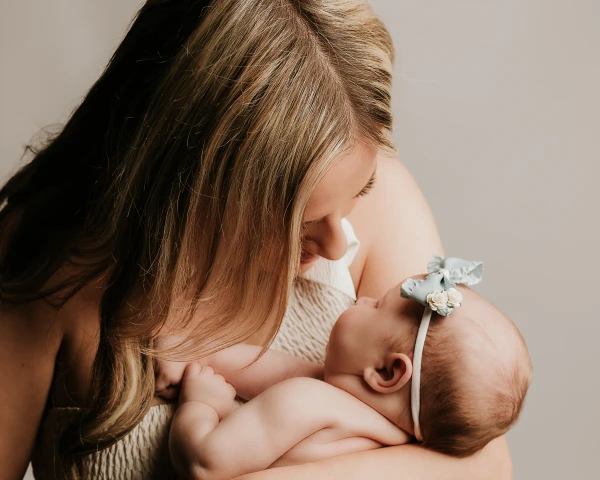 Mum holding closely her newborn in Kamelia's studio